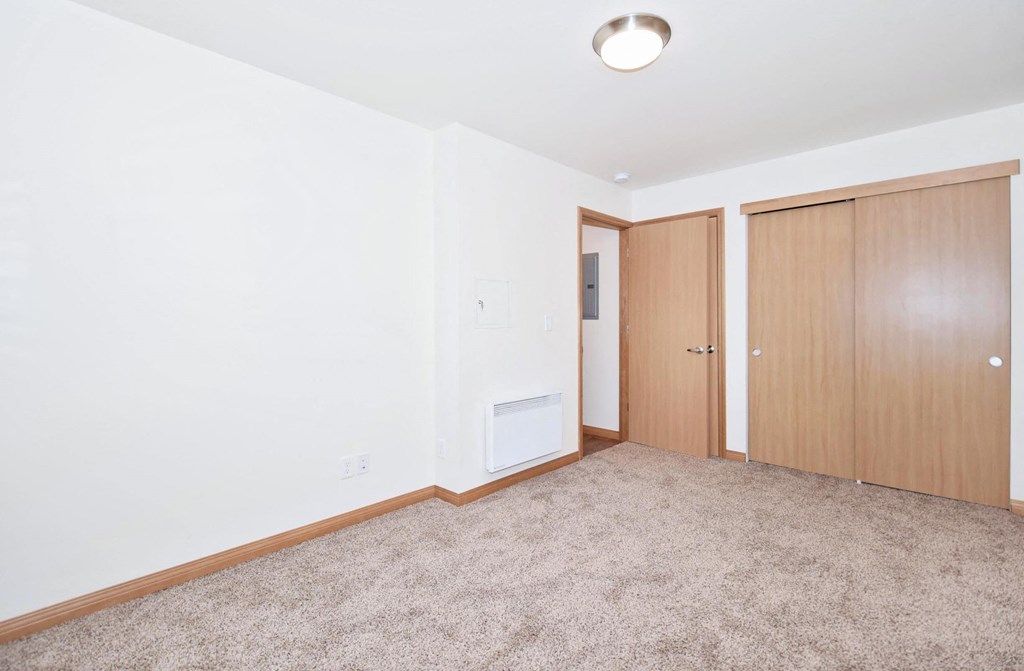 a bedroom with a door to a closet and a carpeted floor