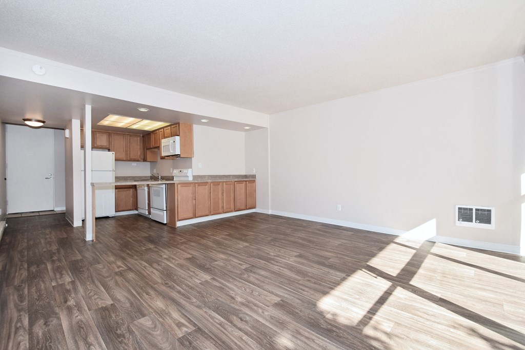 the living room and kitchen of an apartment with wood flooring