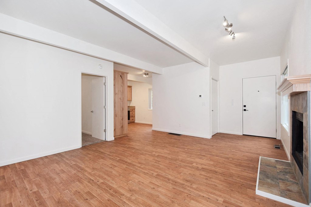 a living room with white walls and wood floors and a fireplace