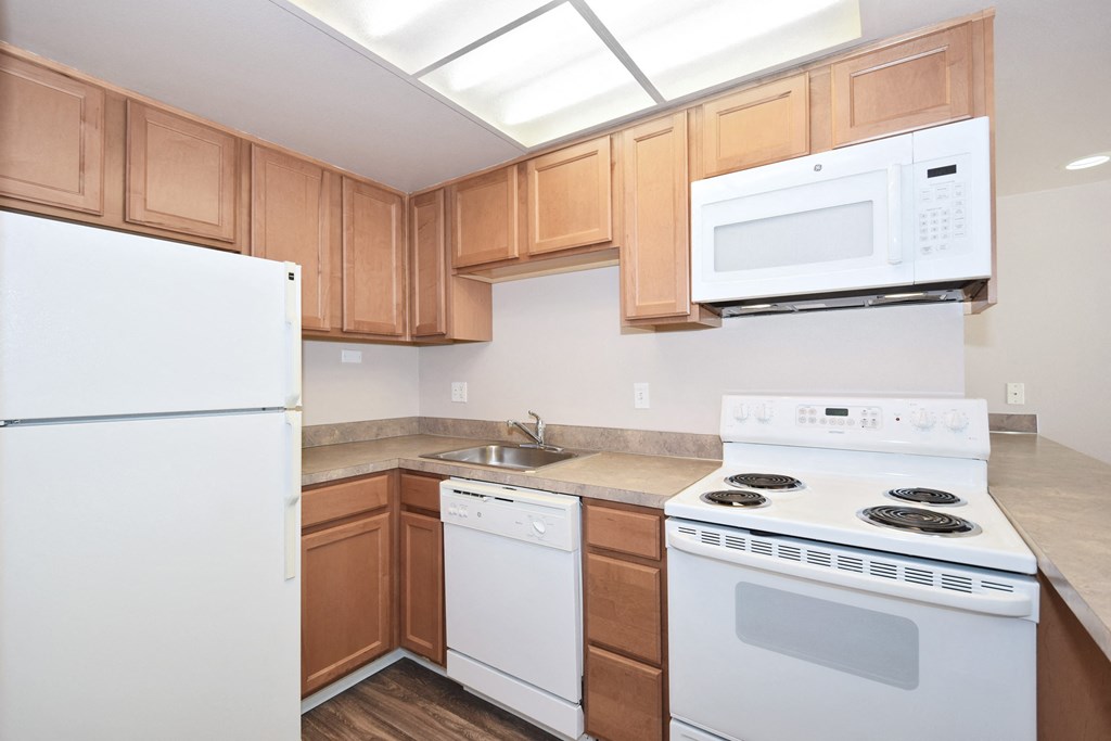 a kitchen with white appliances and wooden cabinets and a white refrigerator