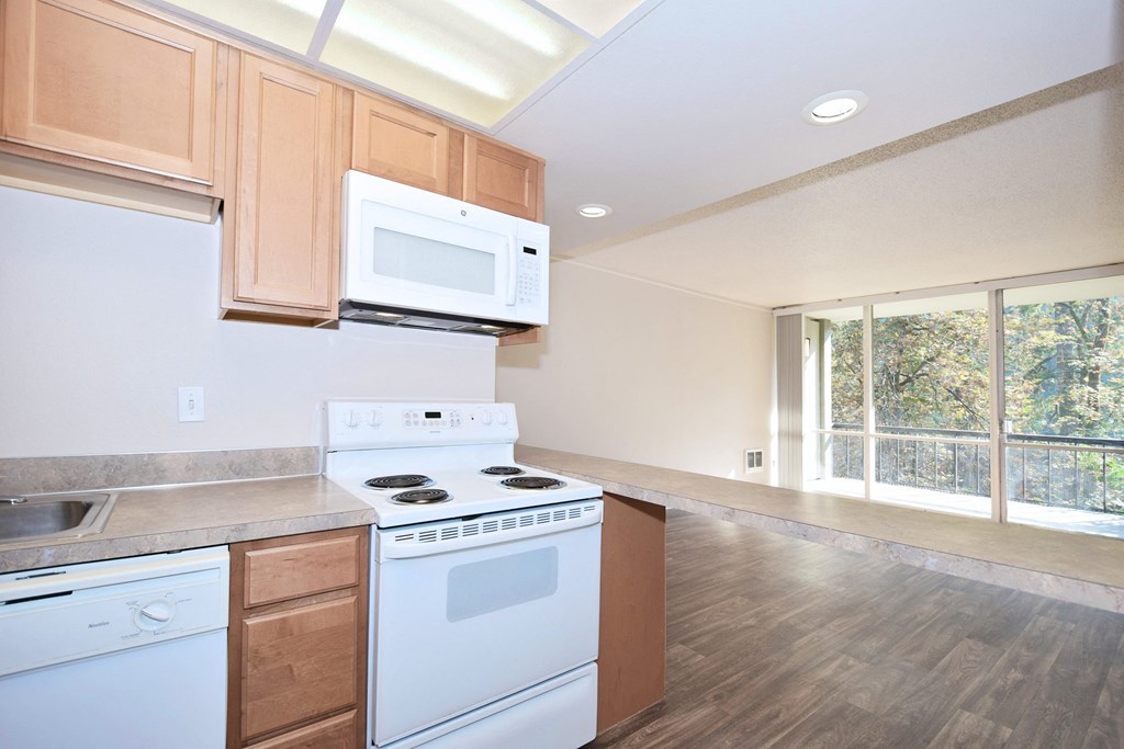 an empty kitchen with white appliances and wooden cabinets