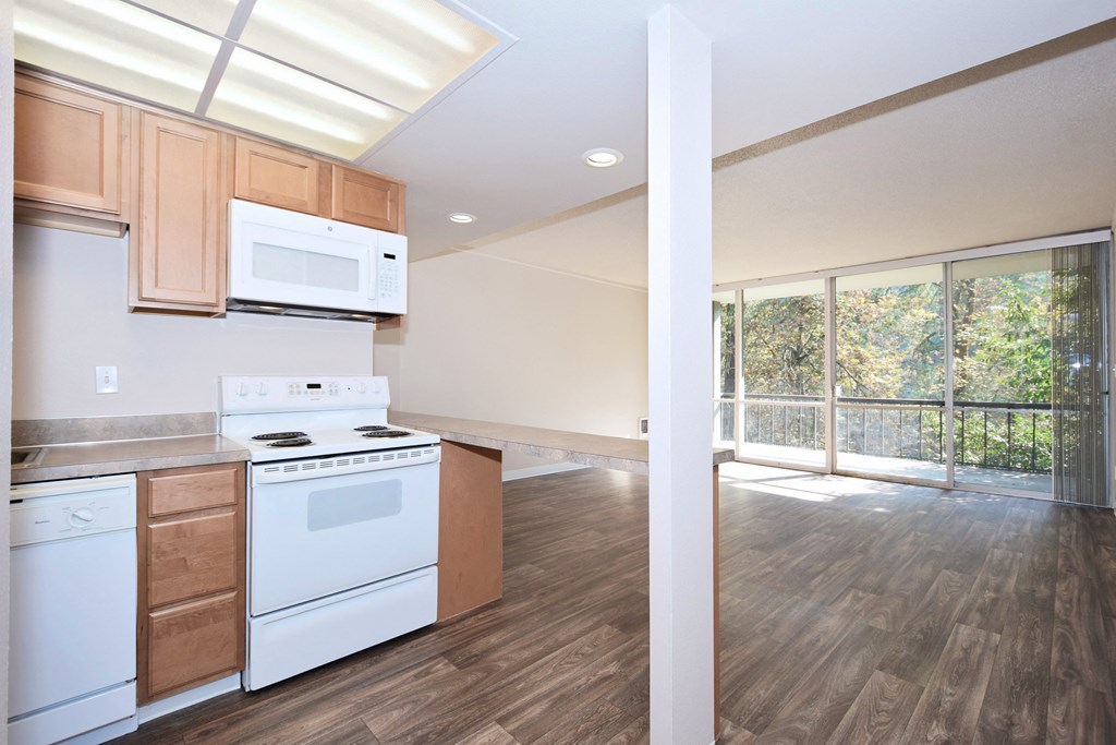 a kitchen with white appliances and wood flooring and a window