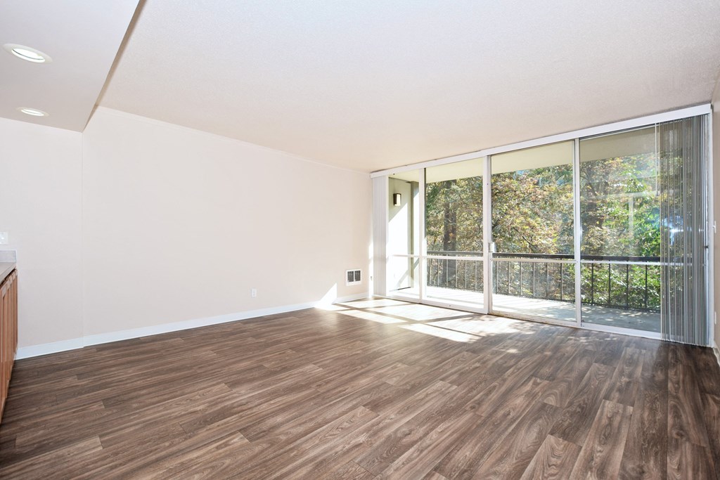 an empty living room with wood flooring and sliding glass doors