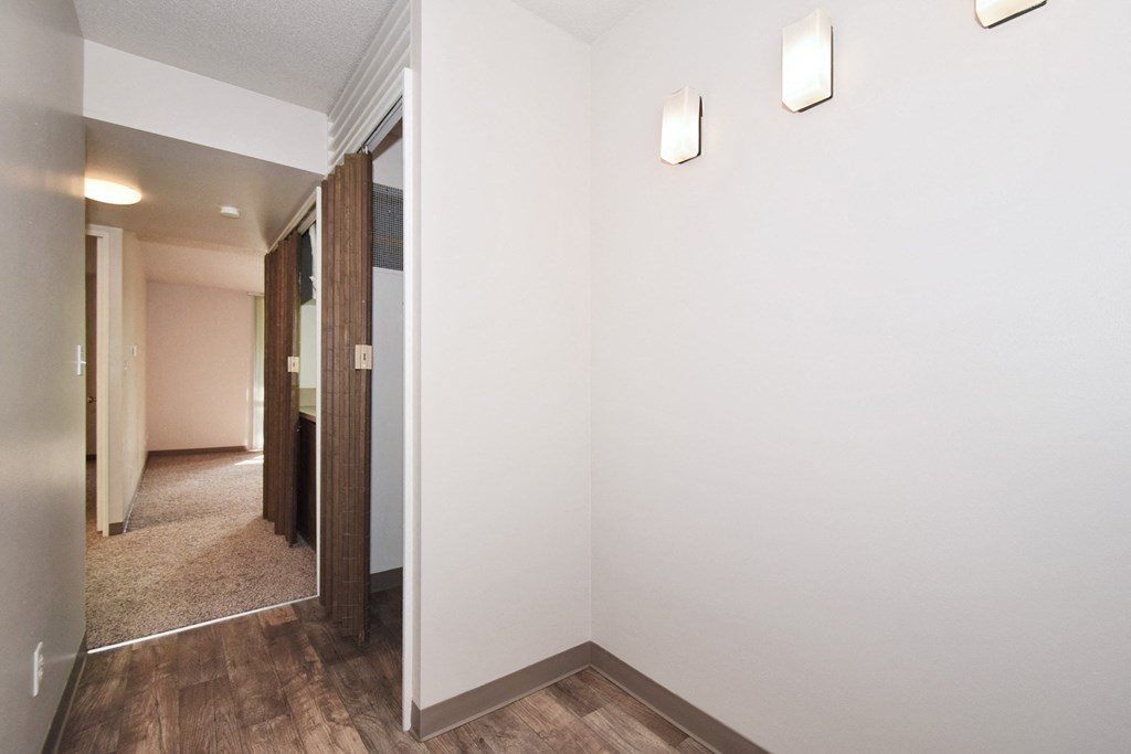a hallway with white walls and wood floors and a mirror