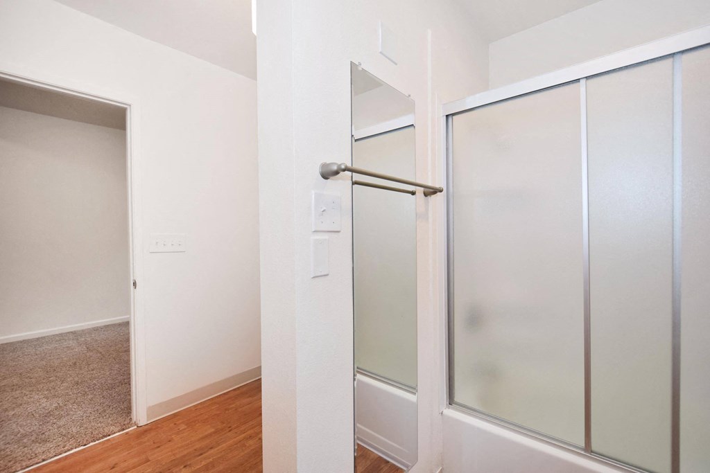 a closet with a glass door and a door to a hallway