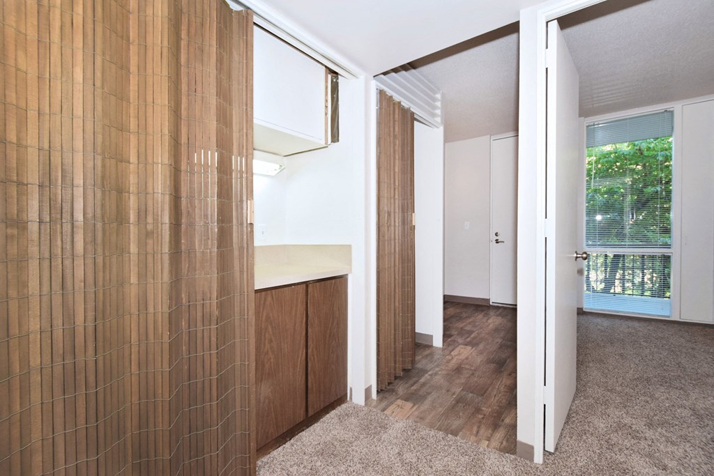 a living room with a door to a kitchen and a window