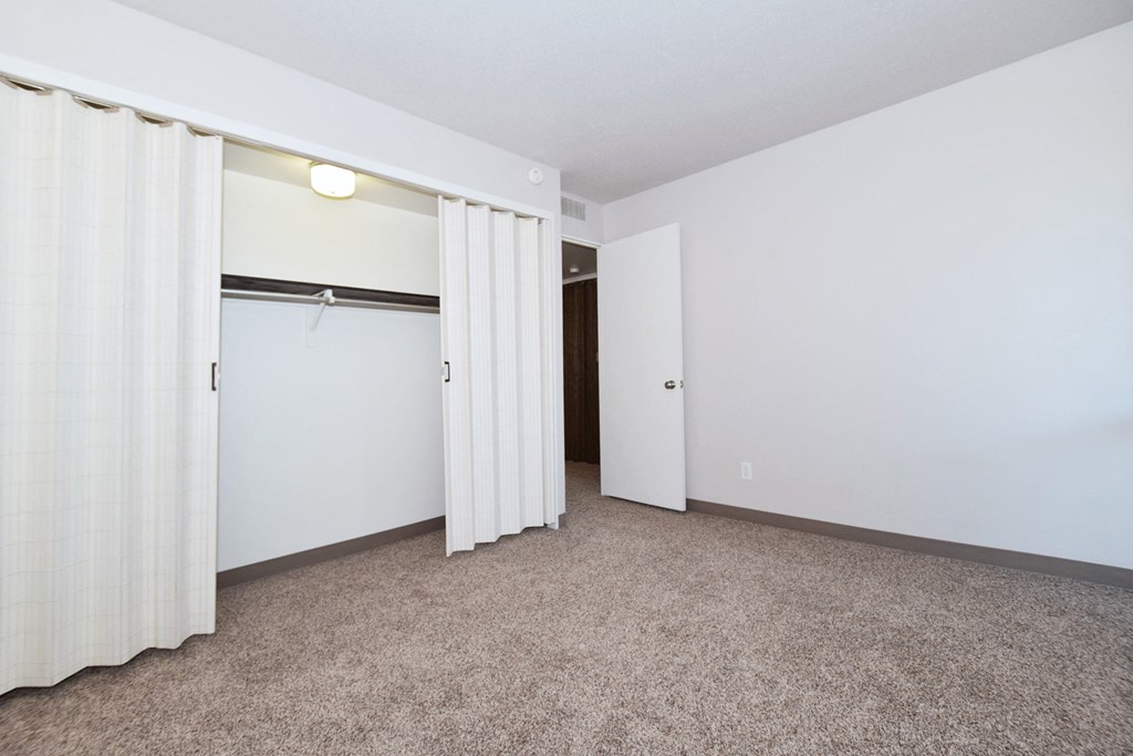 an empty room with white walls and curtains and a closet