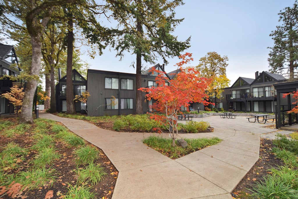 a sidewalk in front of a group of buildings with trees
