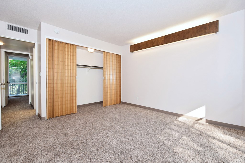 an empty living room with a door to a refrigerator