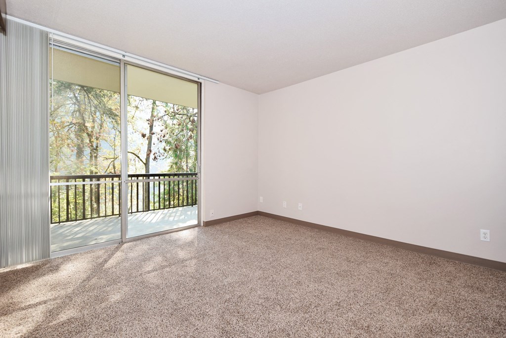 an empty living room with a sliding glass door to a balcony