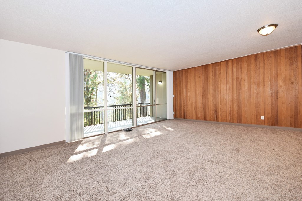 an empty living room with wood paneling and a balcony