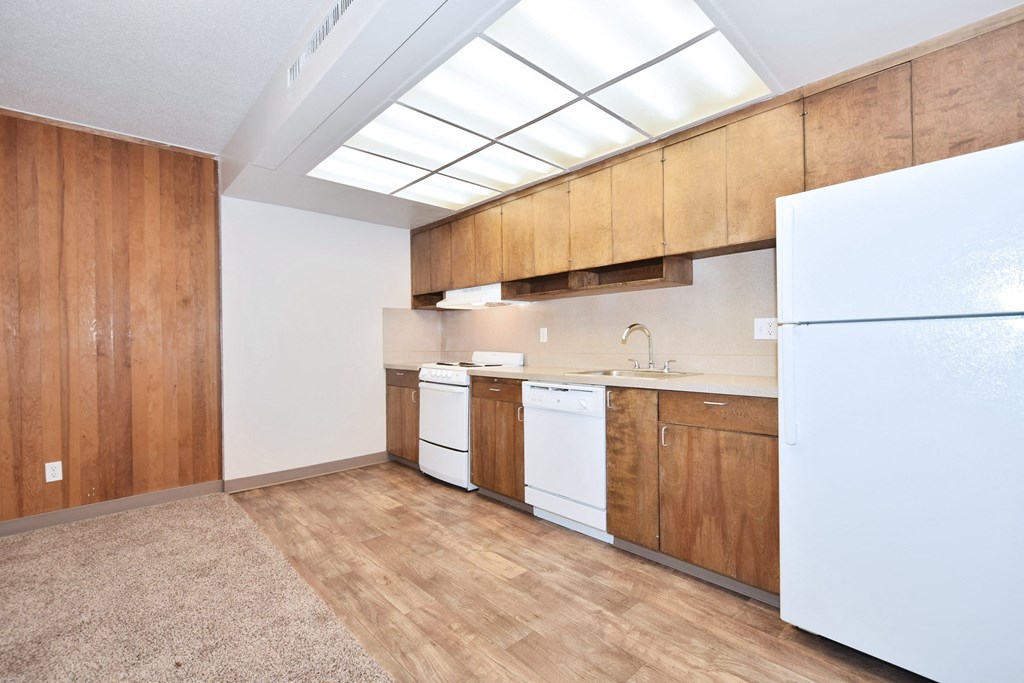 an empty kitchen with white appliances and wooden cabinets
