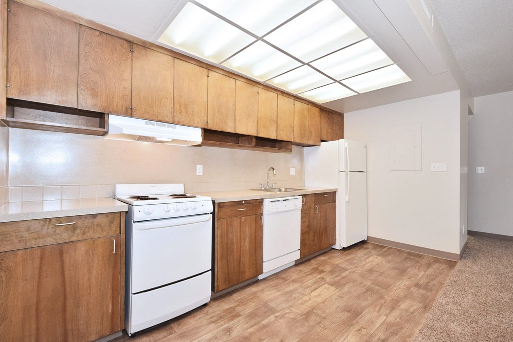 an empty kitchen with white appliances and wooden cabinets