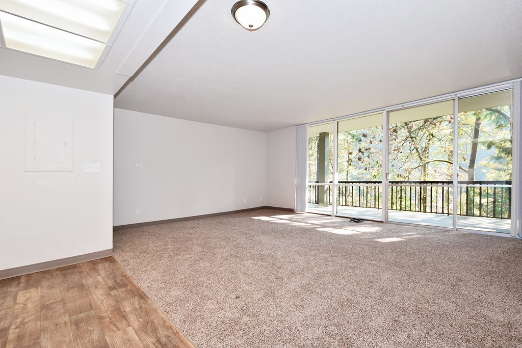 an empty living room with a large window and a balcony