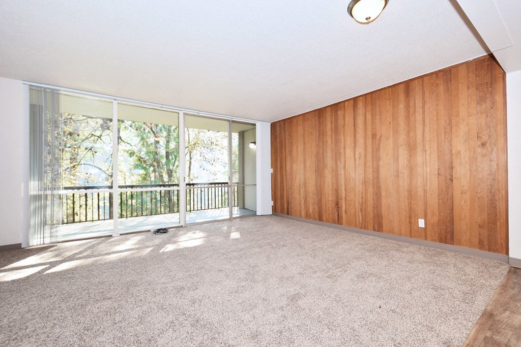 an empty living room with wood paneling and a balcony