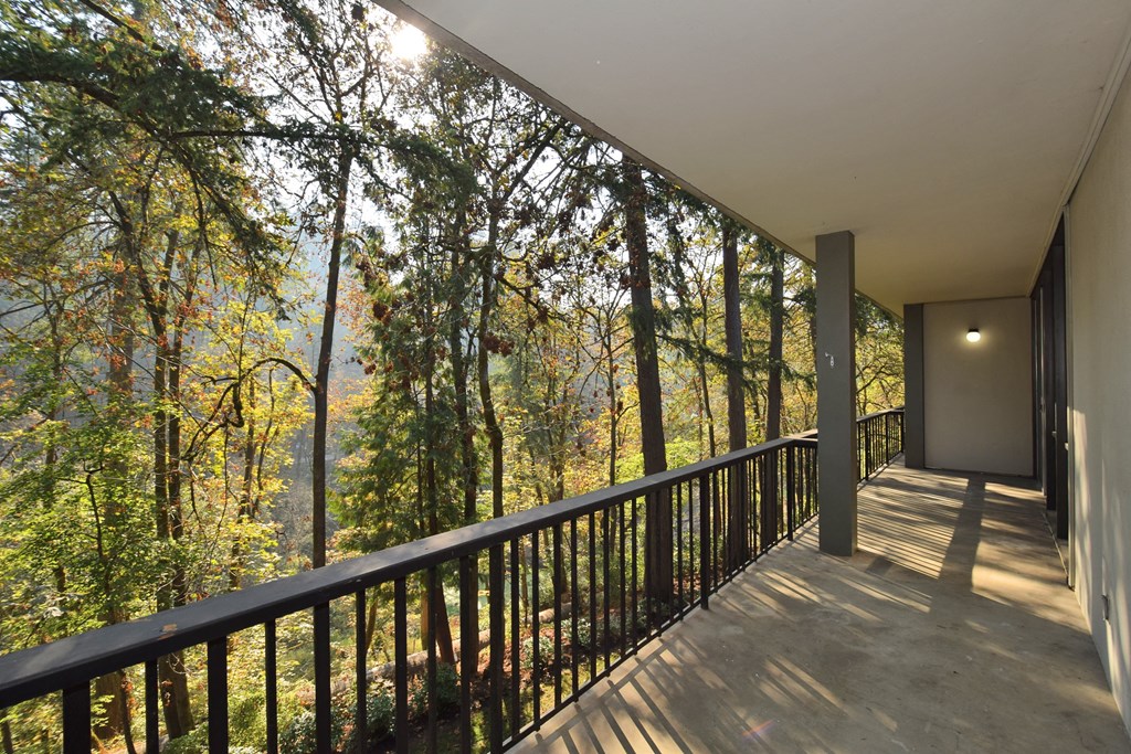 a balcony with a view of a forest and a house