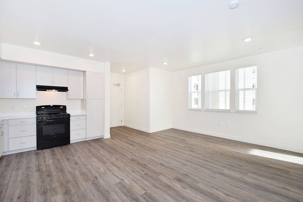 an empty living room and kitchen with white walls and wood flooring
