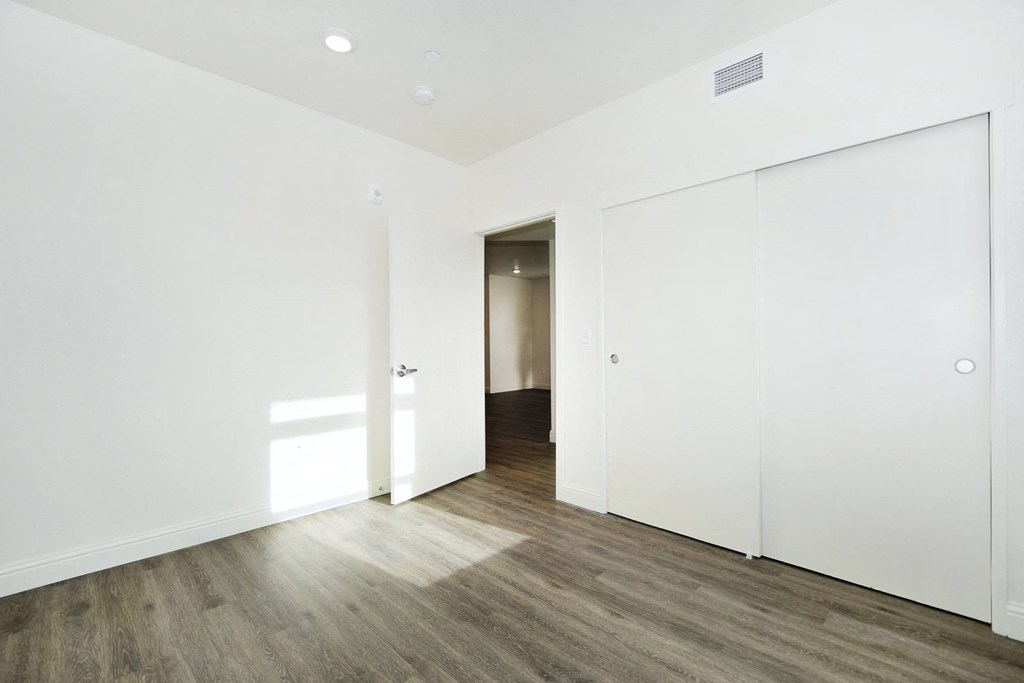 a bedroom with white walls and wood floors