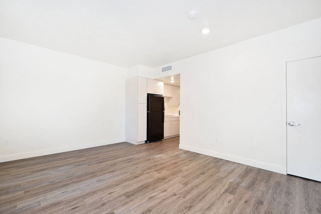 an empty living room with white walls and wood flooring