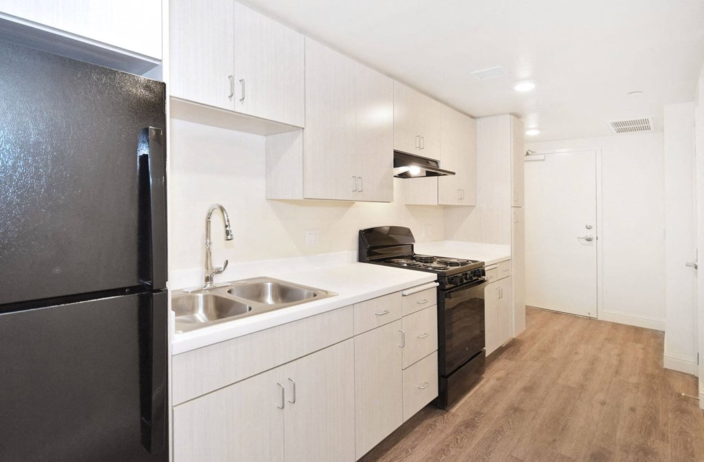 a kitchen and a living room with white walls and a wood floor