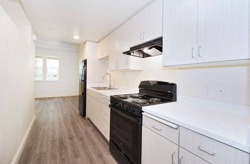 an empty kitchen with white cabinets and a black stove