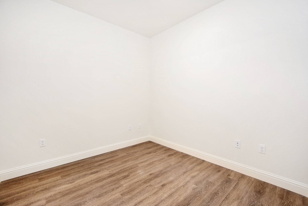 an empty room with white walls and wood floors