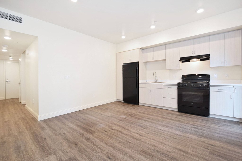 an empty kitchen with white cabinets and black appliances
