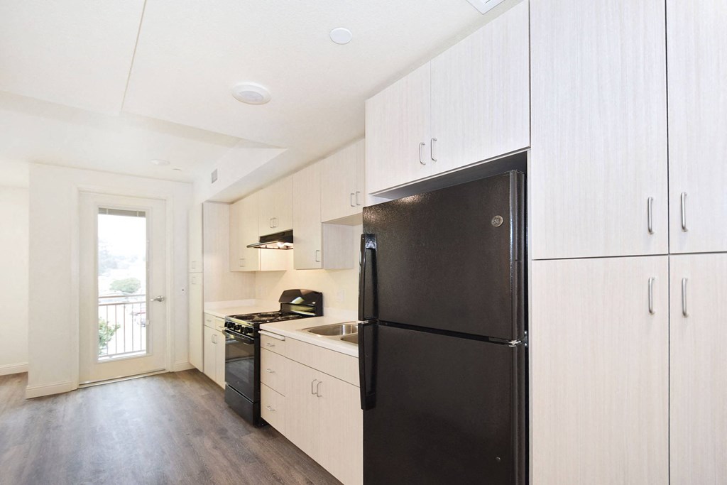 a kitchen with white cabinets and a black refrigerator
