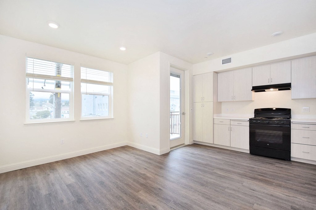 an empty kitchen with white cabinets and a black stove and refrigerator