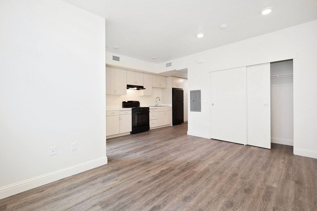 a living room and kitchen with white walls and wood floors