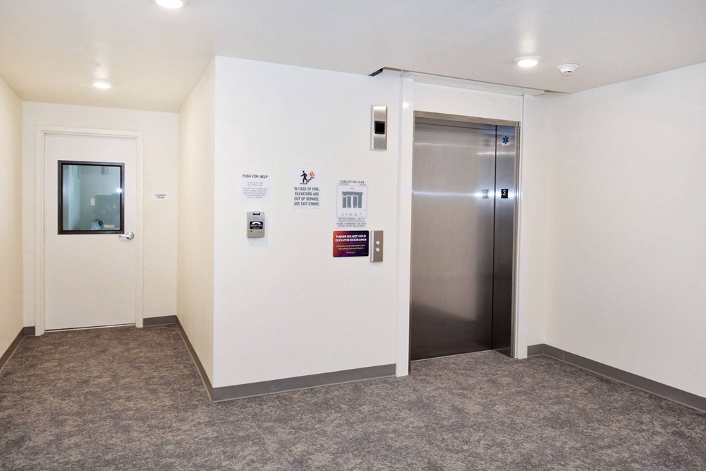 a stainless steel door in a room with a carpeted floor and white walls
