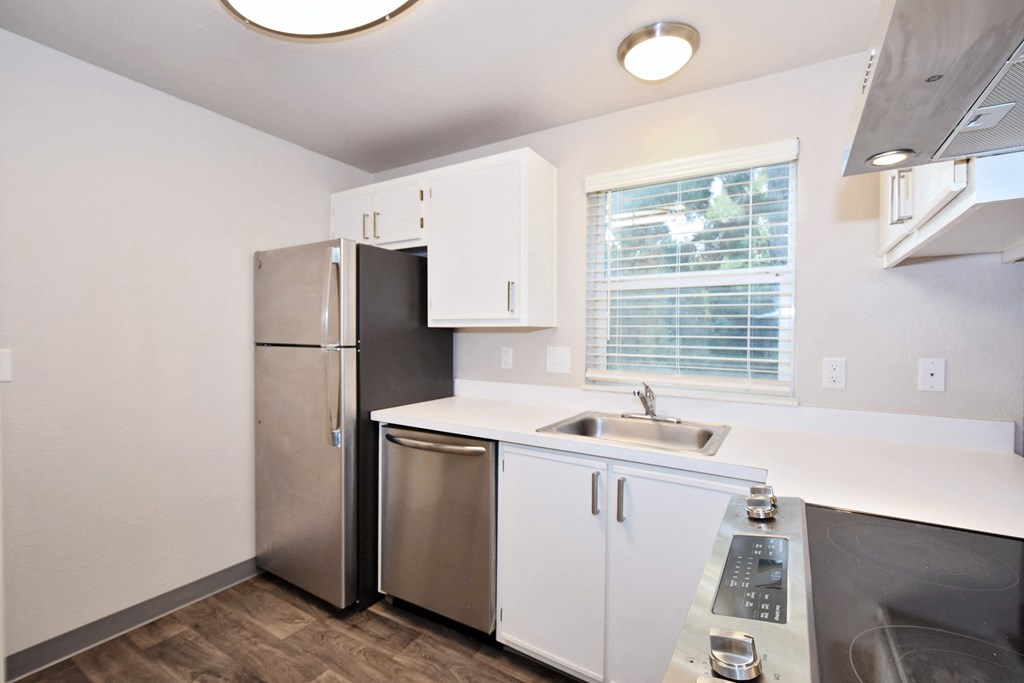 a kitchen with white cabinets and stainless steel appliances and a window