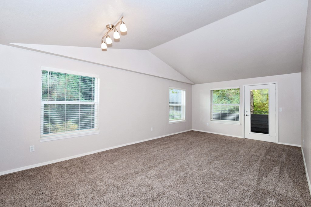 an empty living room with carpet and a door to a patio