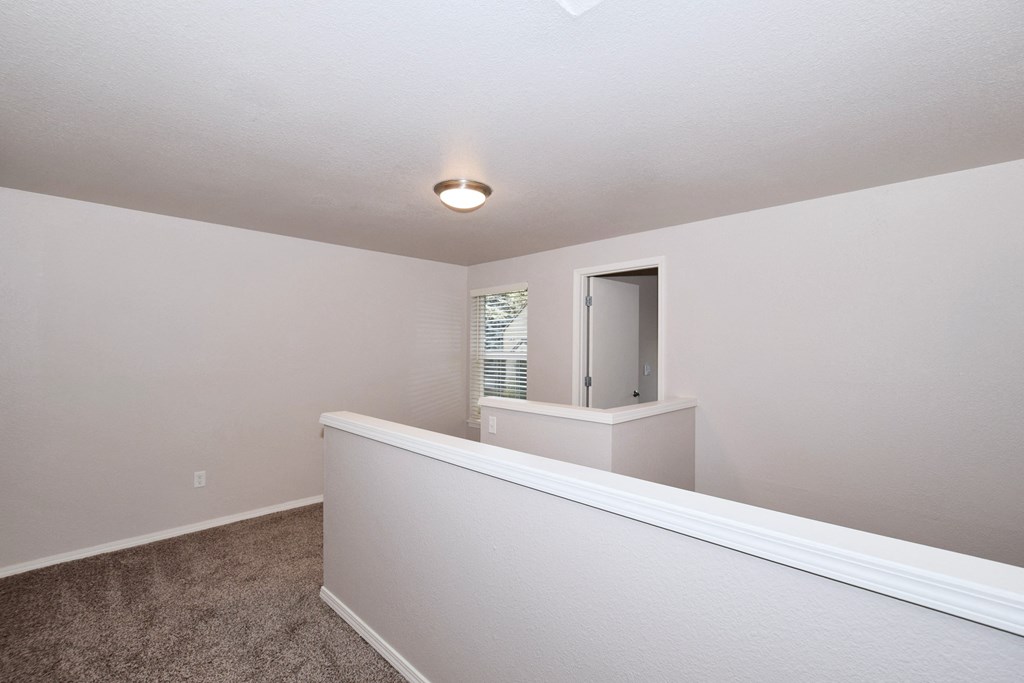 an upstairs room with carpet and a door to a bathroom
