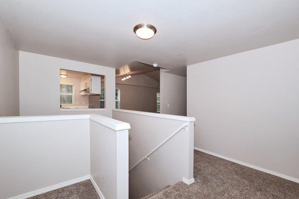 the upstairs landing of a renovated home with white walls and carpeted flooring