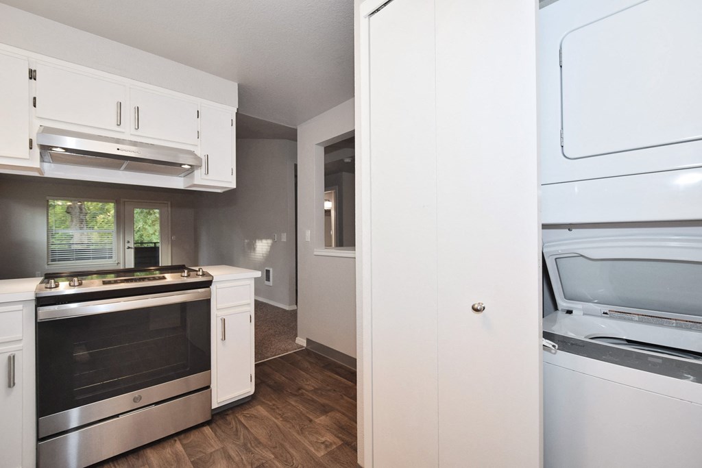 an empty kitchen with white cabinets and stainless steel appliances
