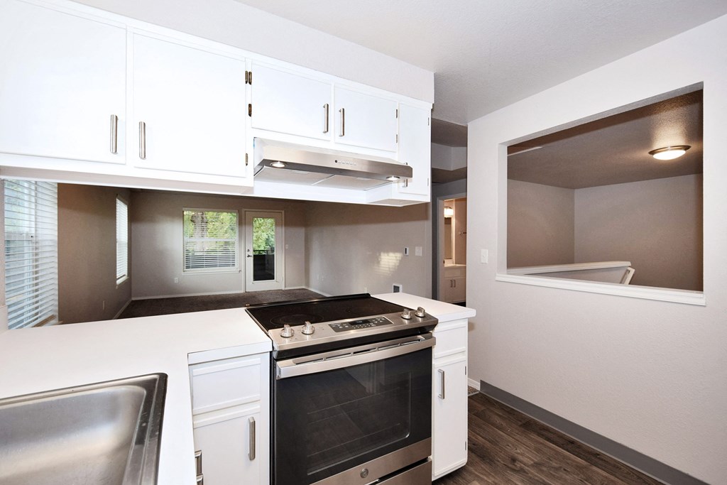 a kitchen with white cabinets and a stove and a window