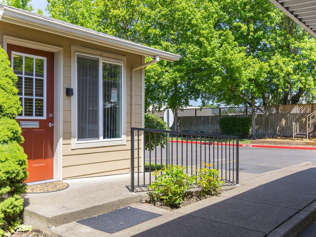 the front of a house with a red door and a black fence