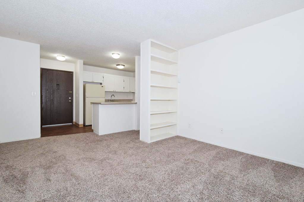 a spacious living room with a kitchen in the background