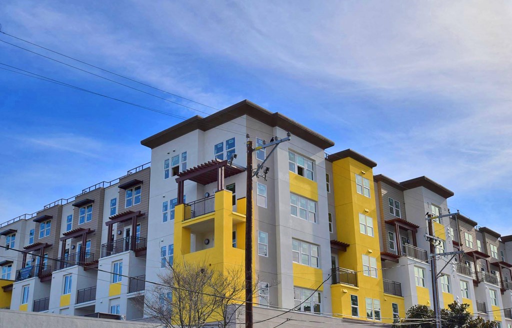 a row of apartment buildings with yellow and white facade and a blue sky
