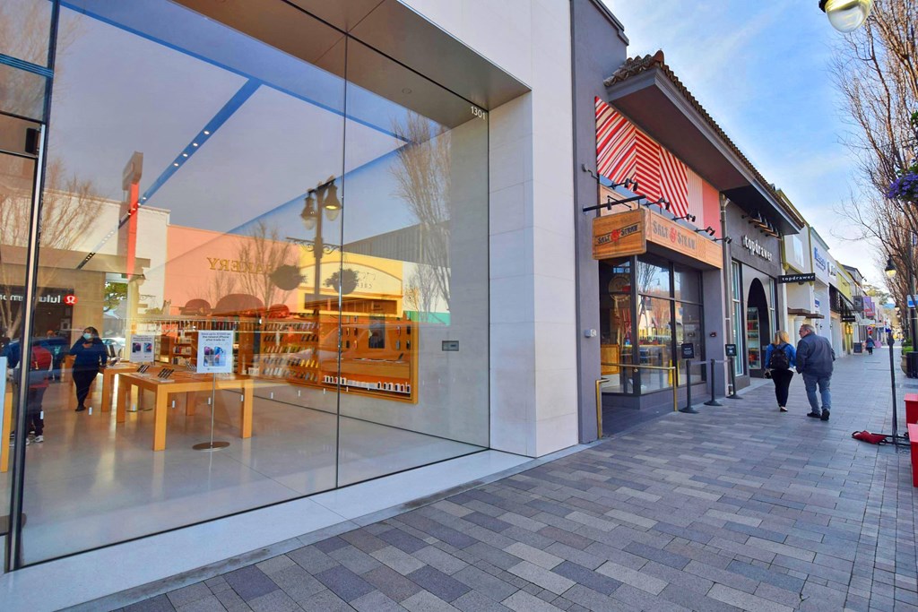 people walking down a sidewalk in front of a glass building