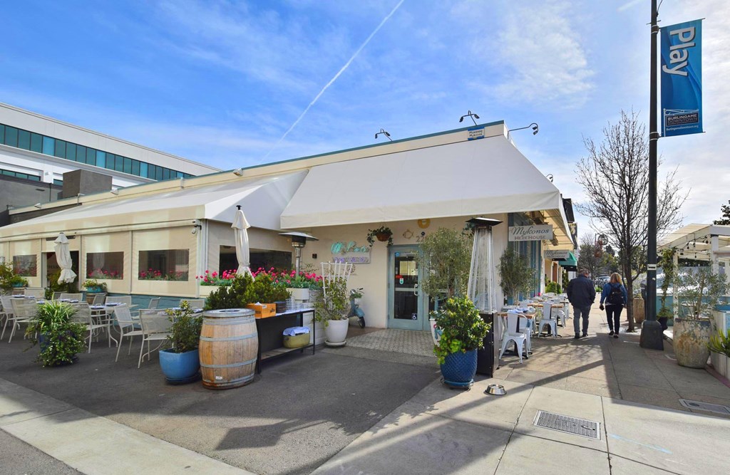 the outside of a restaurant with tables and chairs and awning