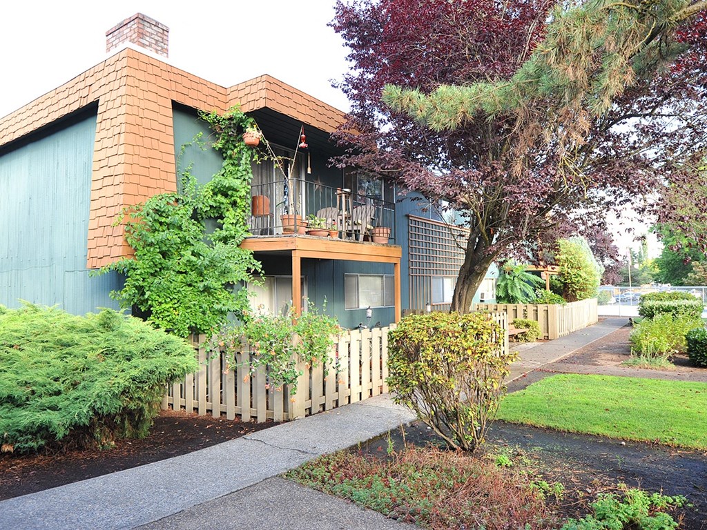 a house with a fence and a tree in front of it