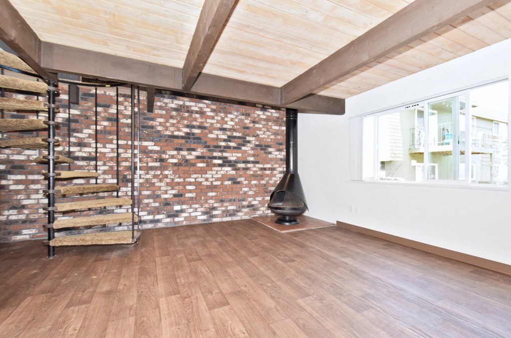 a fireplace in a living room with wood floors and a brick wall