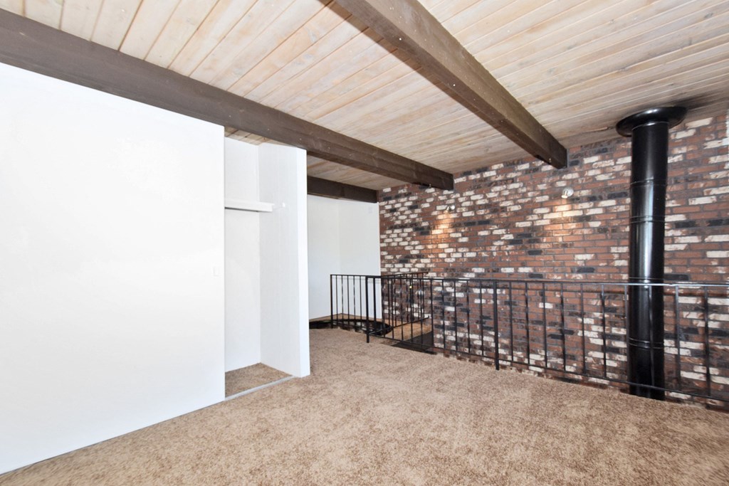 a loft with a brick wall and a wood ceiling