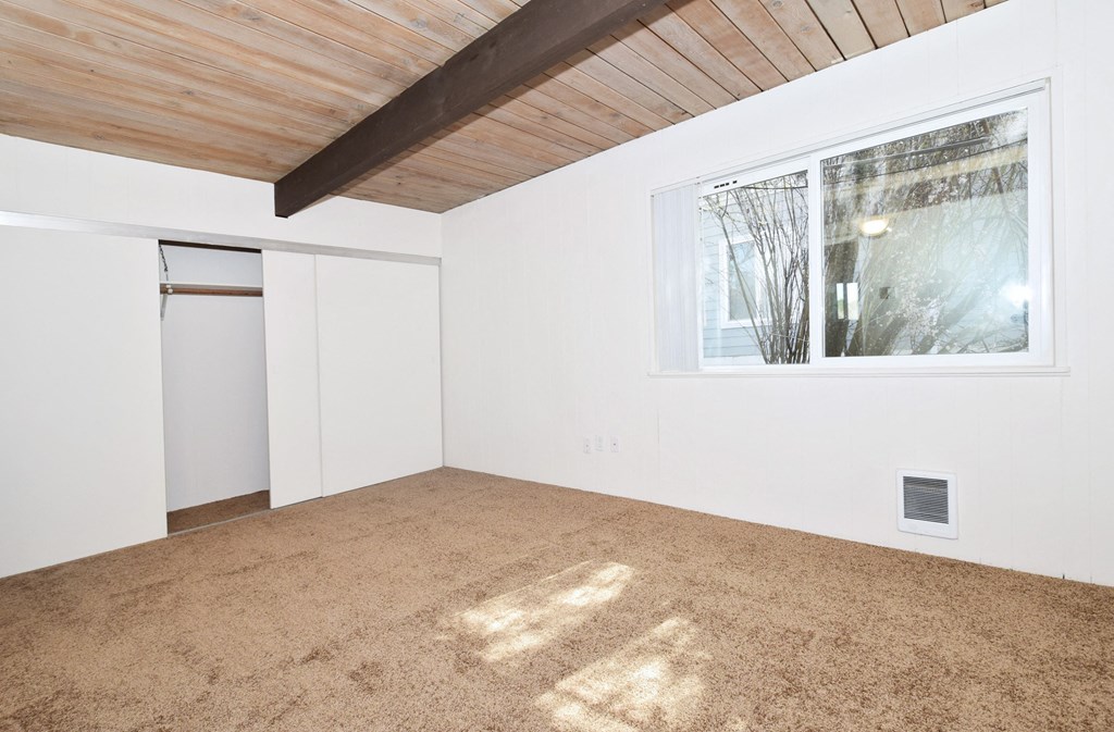 a bedroom with white walls and a large window