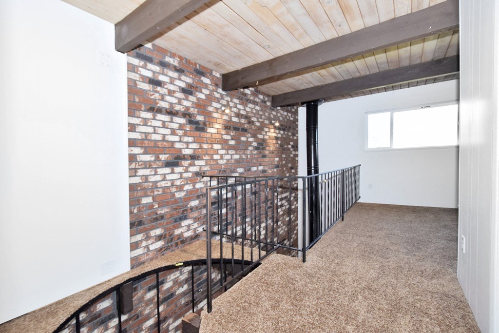 a view from the top of a staircase in a house with a brick wall