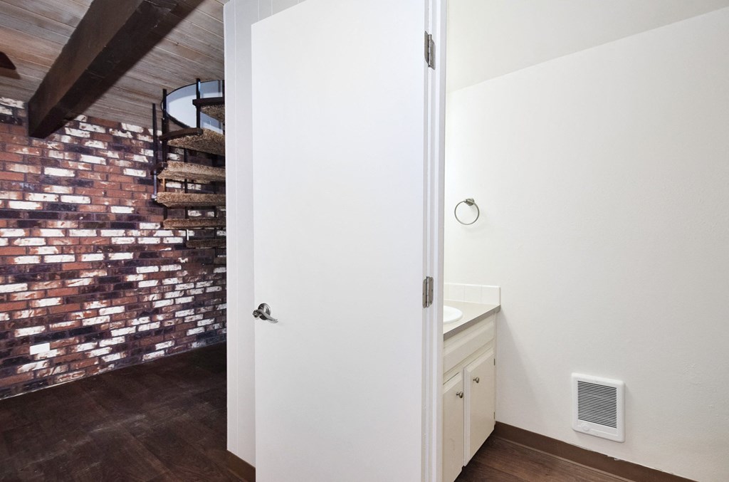 a bathroom with a white sink and a brick wall