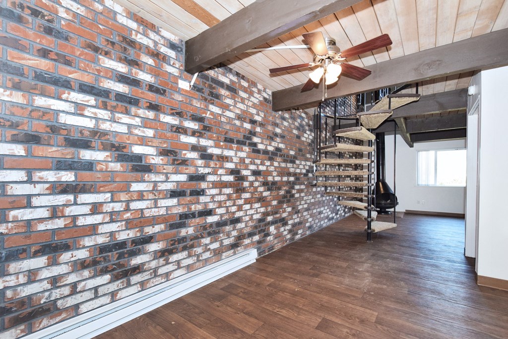 Menlo Manor: brick accent wall in a living room with a wooden floor and a spiral staircase