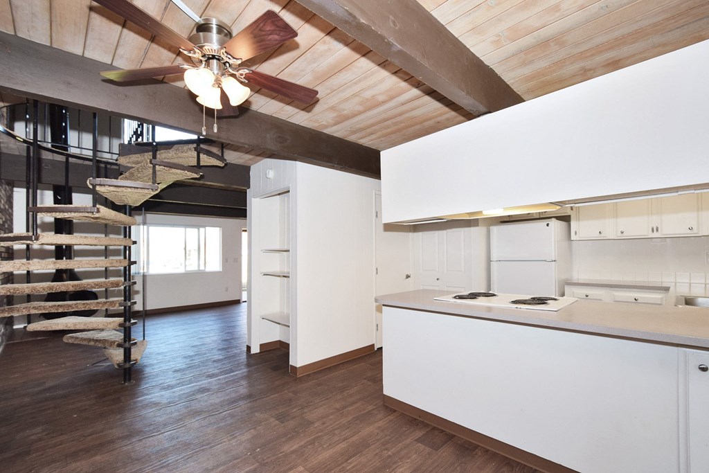 Menlo Manor: kitchen with white cabinets and a white counter top and a spiral staircase in the background